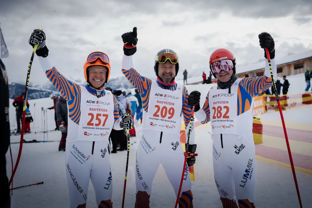 Drei Rennläufer desselben Ski-Teams jubeln mit erhobenen Armen