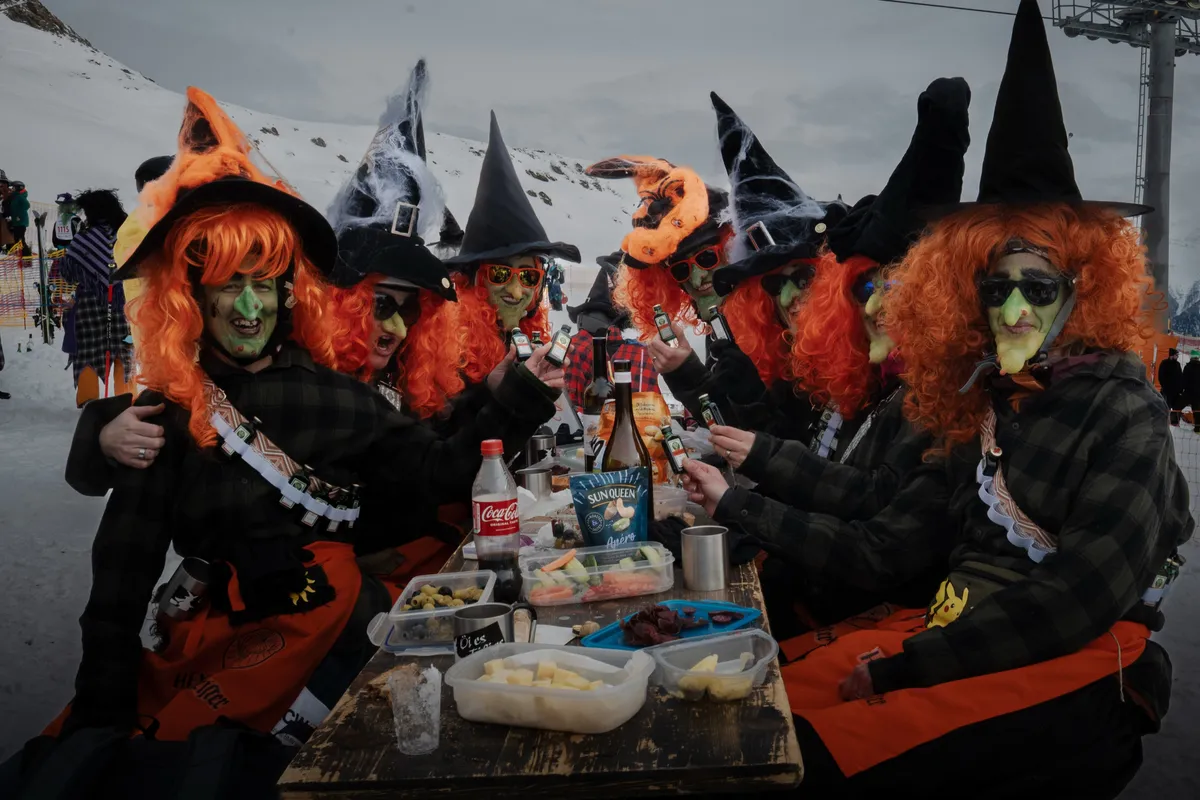Hexengruppe mit orangen Perücken beim Apéro am Holztisch