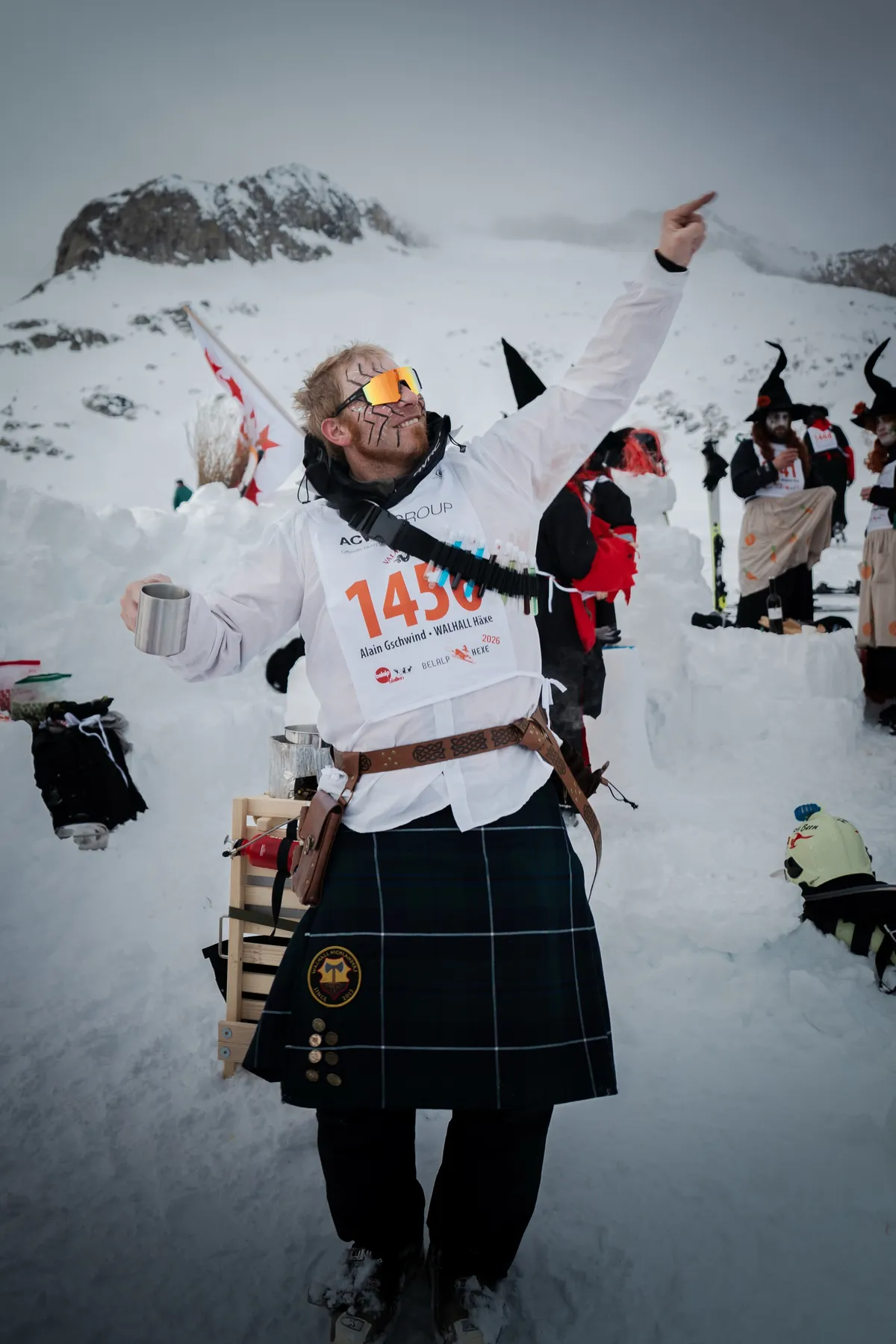 Teilnehmer im Schottenrock zeigt mit dem Becher in der Hand nach oben