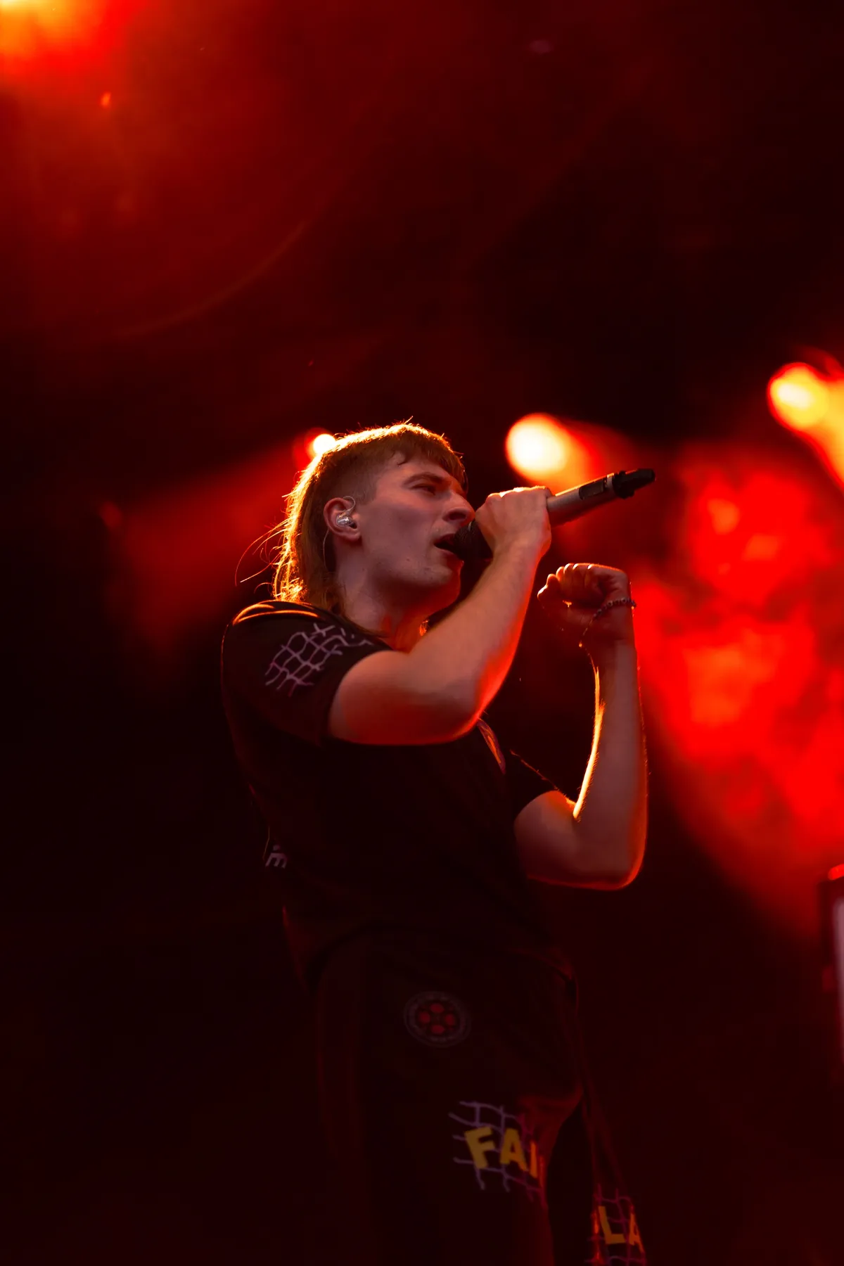 Jule X singt mit erhobener Faust vor roten Lichtkegeln