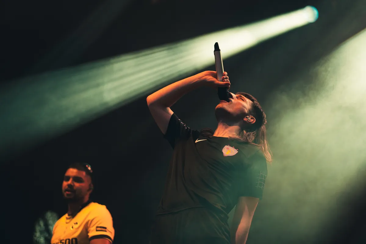 Jule X singt mit hoch erhobenem Mikrofon, links Anru