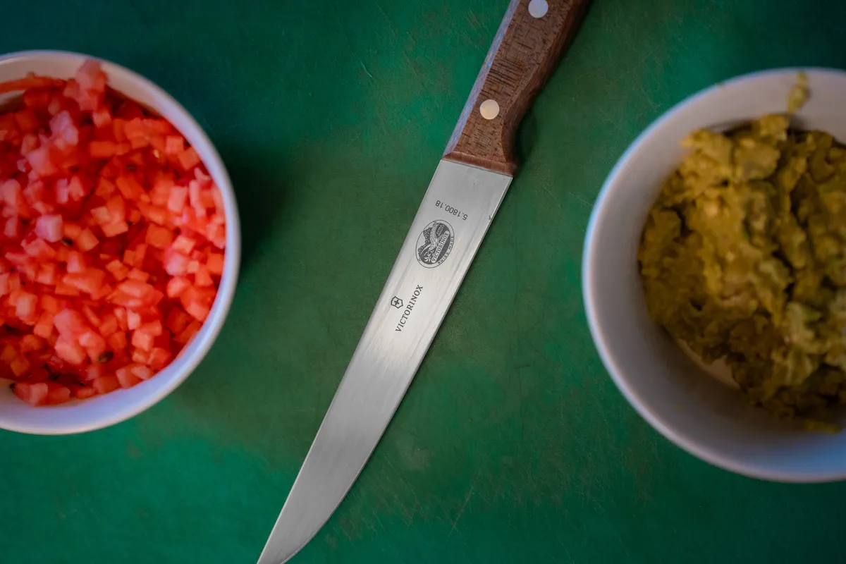 Messer zwischen Schälchen mit gewürfelter Wassermelone und Avocadocreme
