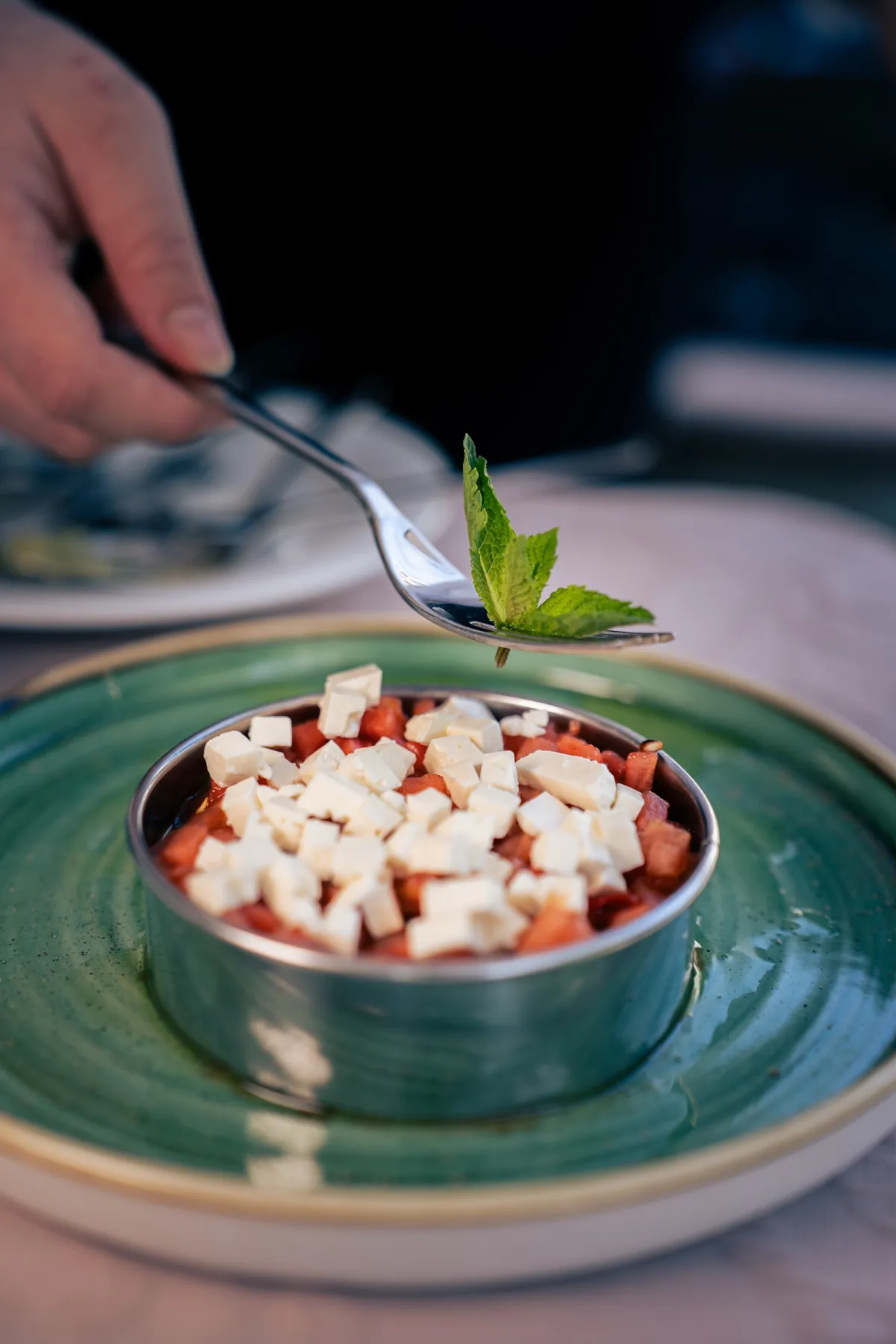 Minze wird mit der Gabel auf das Tartar mit Feta gesetzt