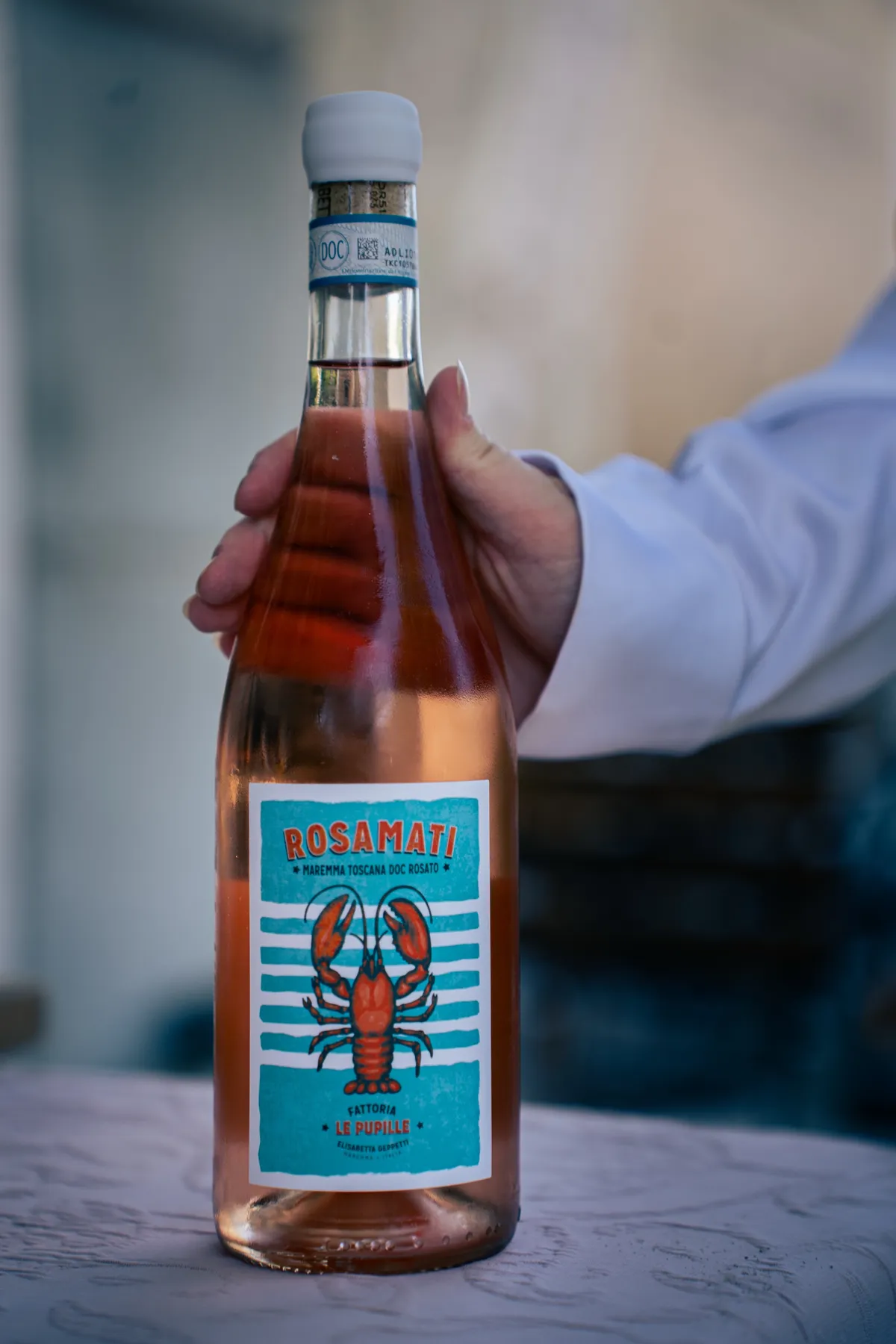Eine Flasche Rosé wird zur Präsentation in den Händen gehalten