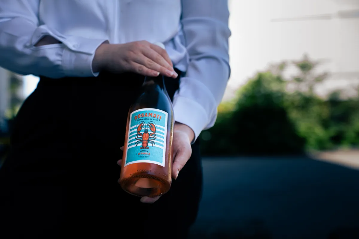 Die Serviceperson präsentiert die Roséflasche mit dem Etikett nach vorn