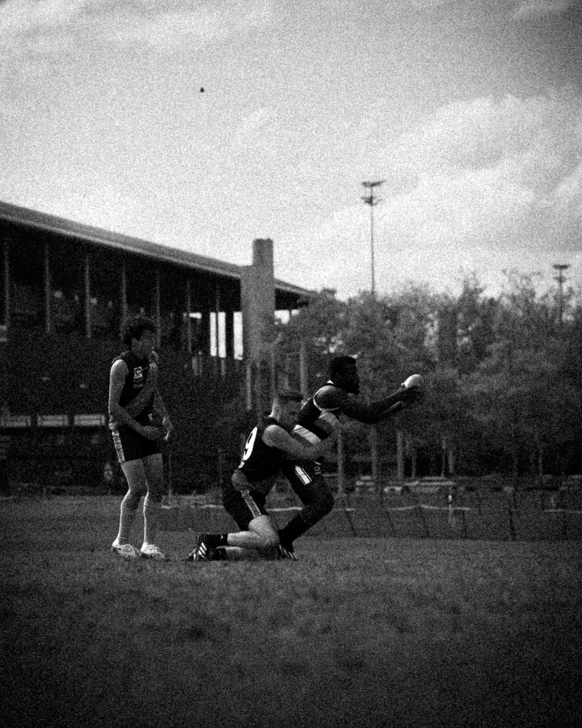 Schwarzweiss: Ein Spieler nimmt den Ball im Tackle an, hinter ihm die Tribüne