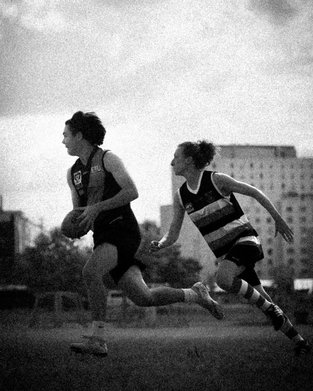Schwarzweiss: Zwei Spielerinnen im Sprint, die vordere trägt den Ball