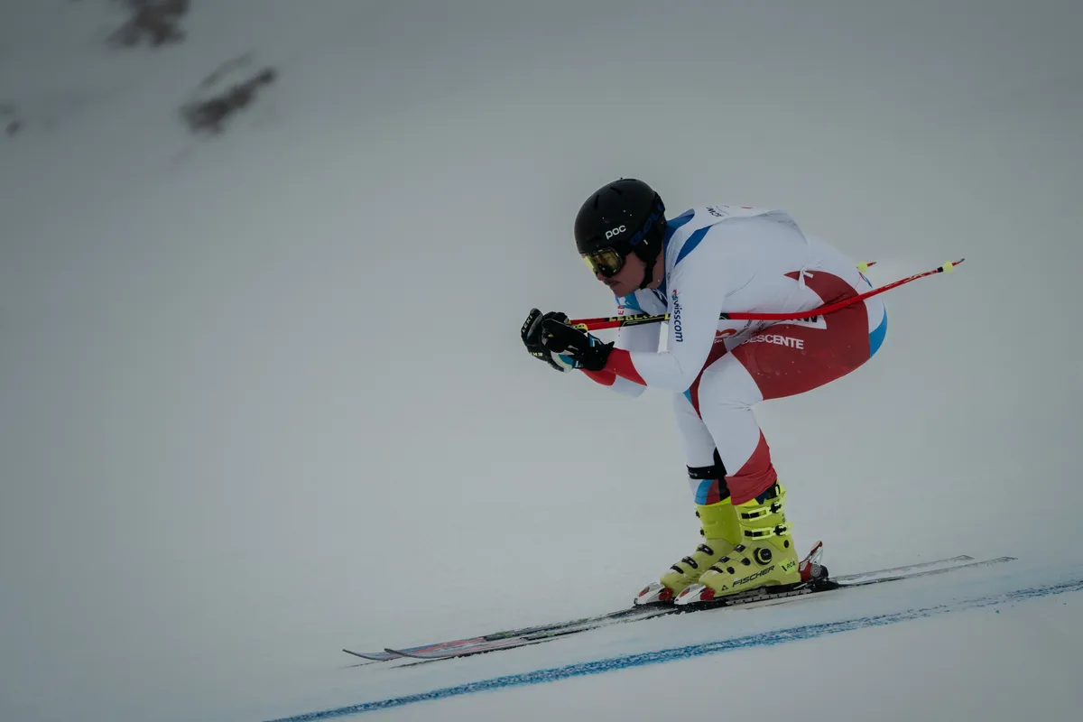 Rennläufer in tiefer Abfahrtshocke dicht über den Ski