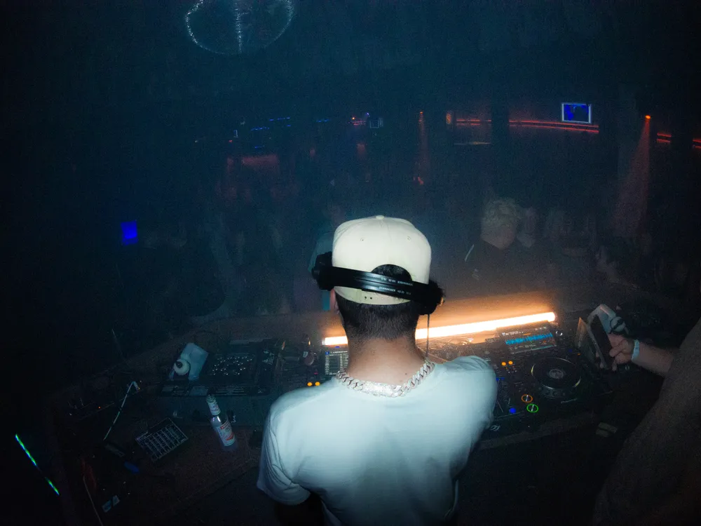DJ Pereira am Mischpult im Loft Thun, farbiges Bühnenlicht