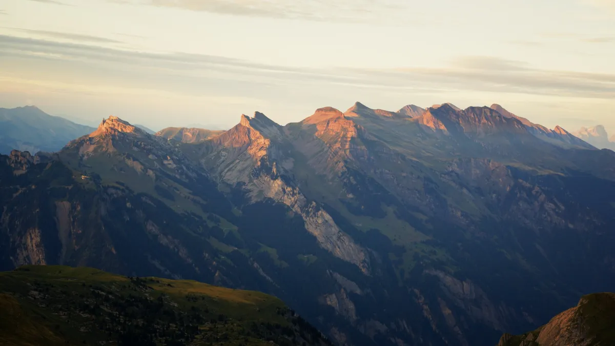 Filmstill: Alpenglühen über einer Bergkette, die Felswände leuchten rötlich